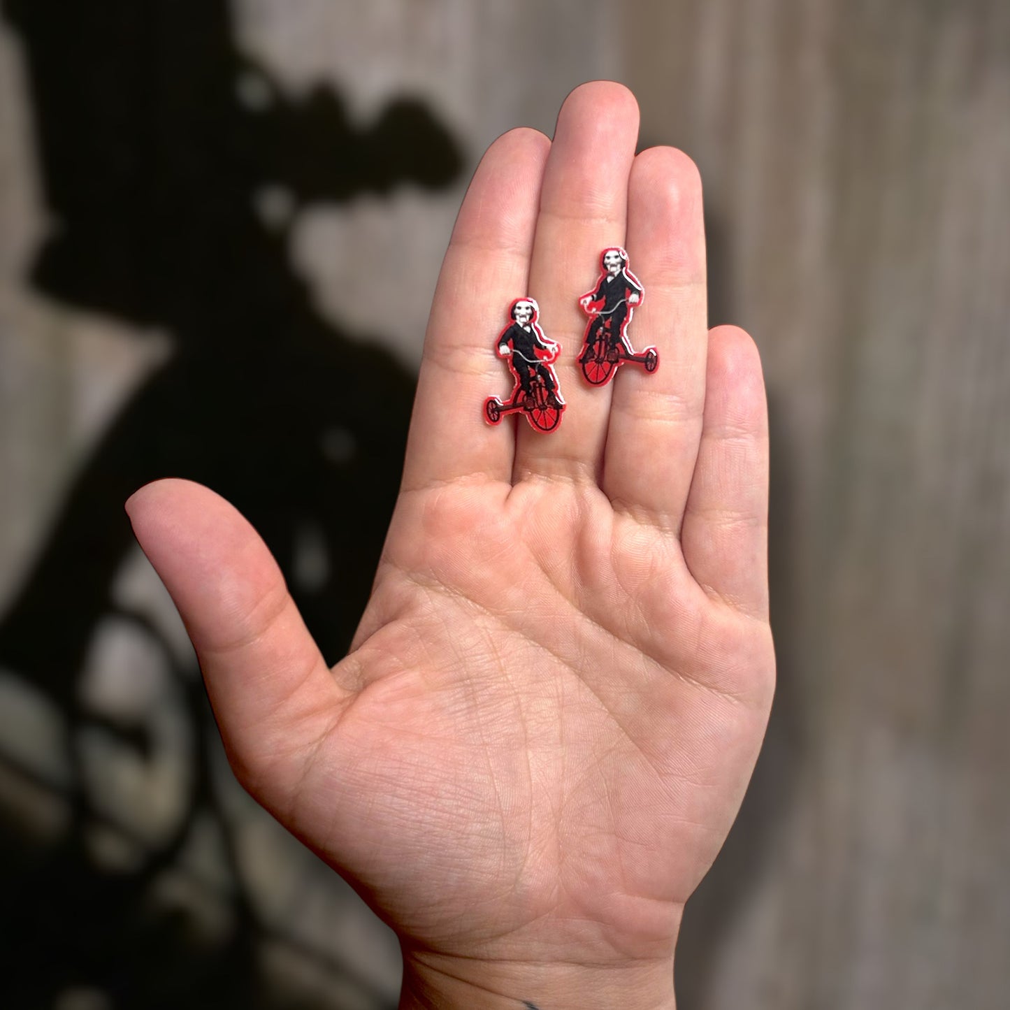 SAW Billy riding tricycle creepy puppet resin stud earrings being held