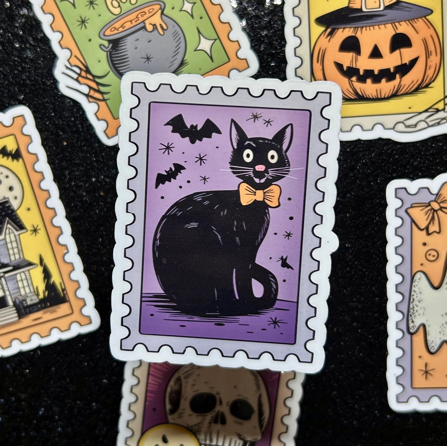 Sticker of a black cat wearing an orange bowtie on a purple background surrounded by similar Halloween-themed stamp stickers.