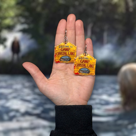 Friday the 13th-inspired bloody Camp Crystal Lake sign resin statement earrings being held