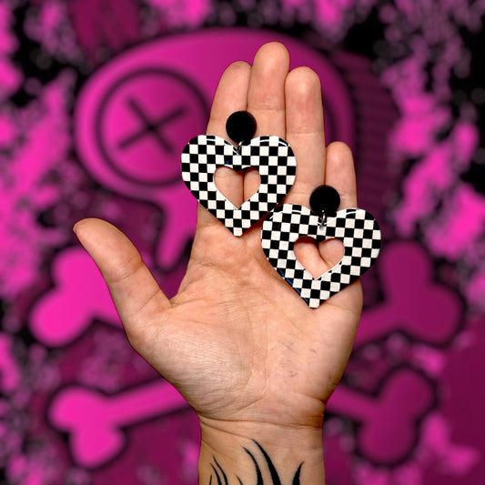 Black-and-white checkerboard mod heart resin statement earrings being held