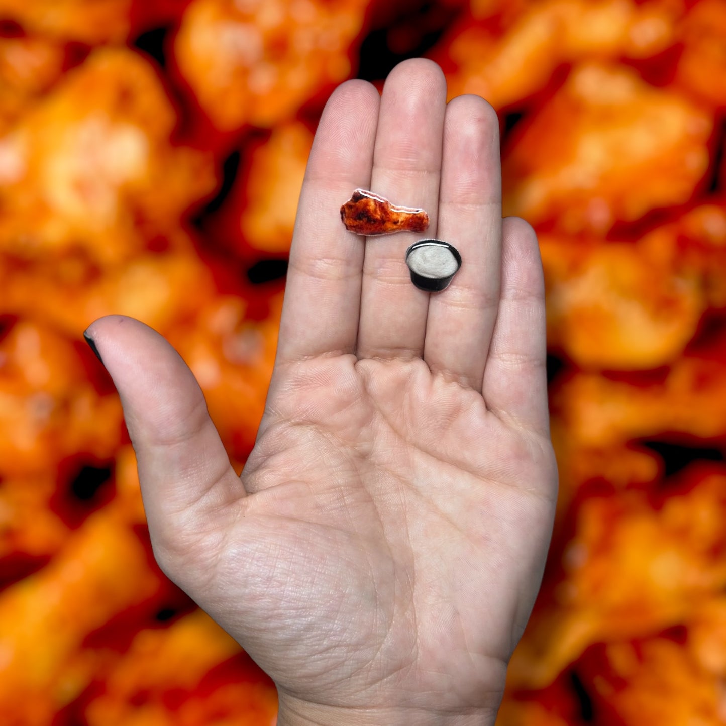 Chicken wing and ranch cup resin stud earrings being held