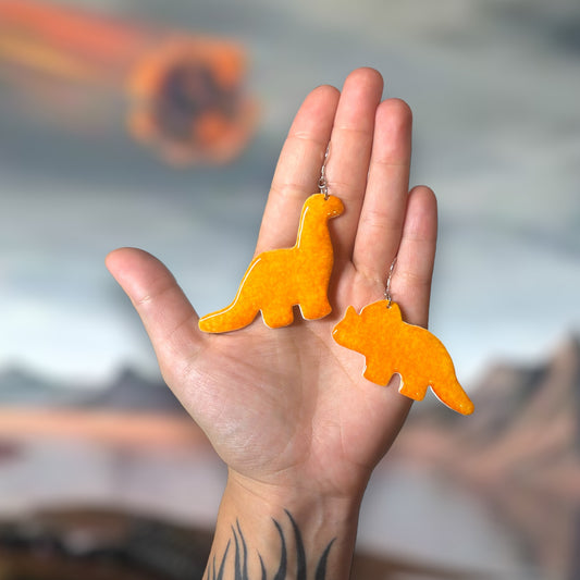 Dinosaur chicken nugget mismatched resin statement earrings being held