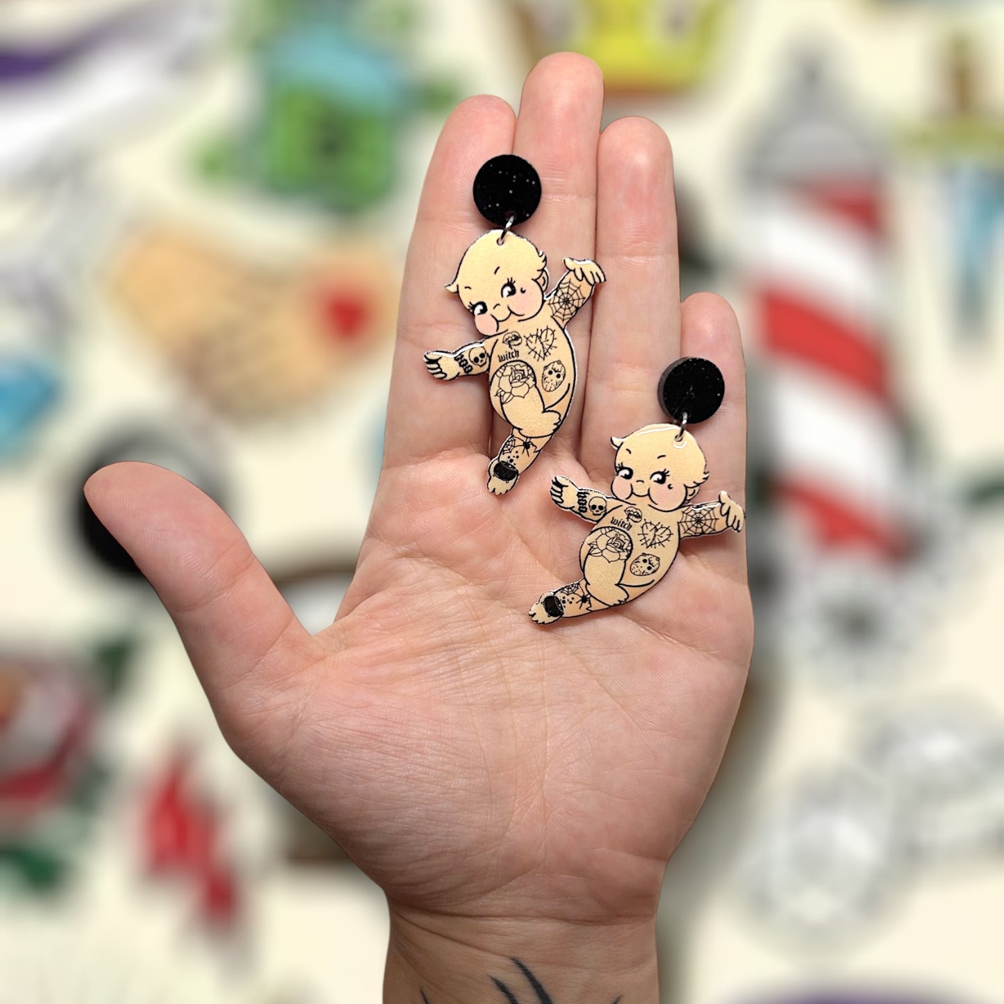 Tattoo kewpie resin statement earrings being held
