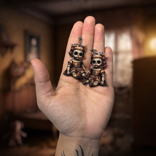 Creepy haunted doll resin statement earrings being held
