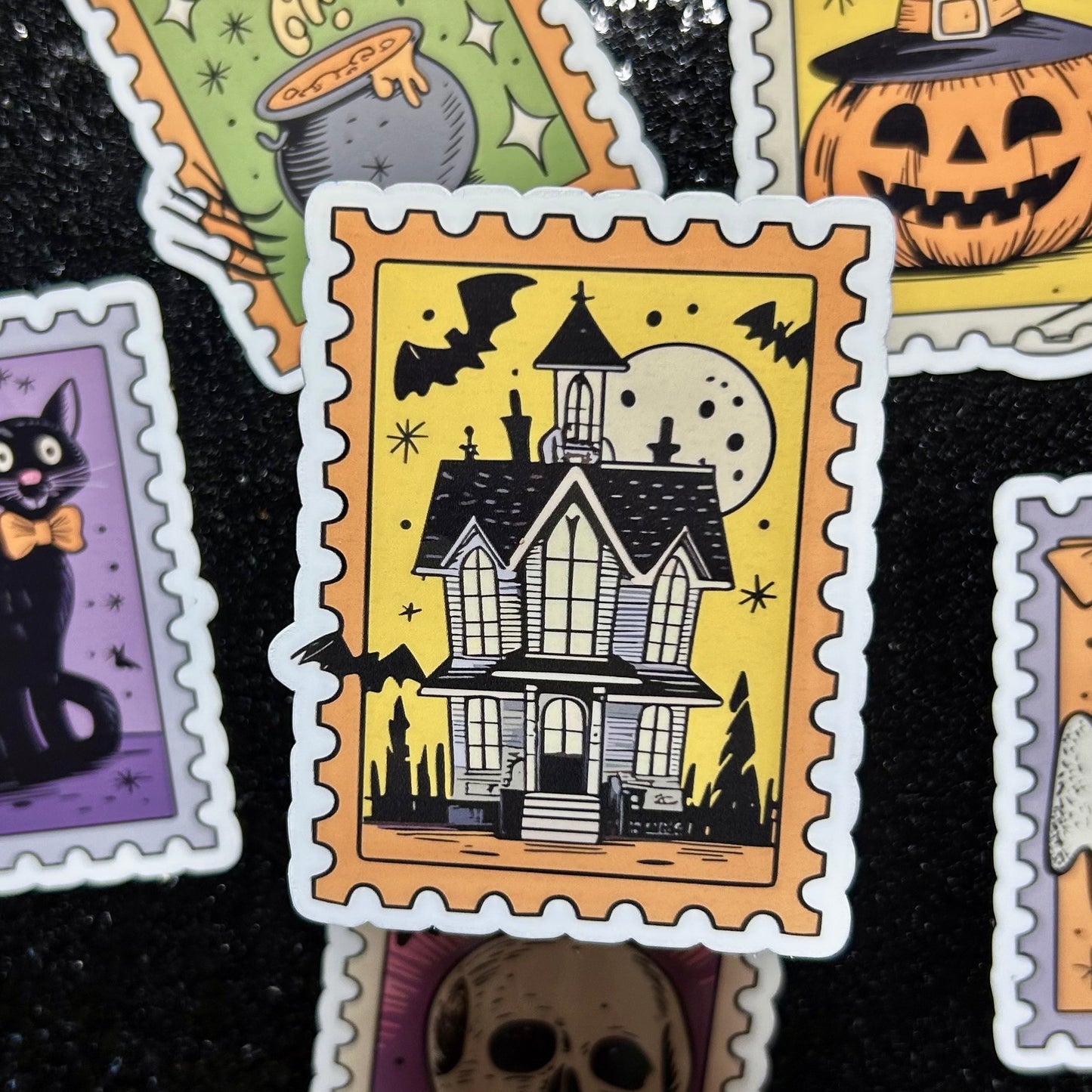 Sticker of a haunted house on a yellow background surrounded by similar Halloween-themed stamp stickers.