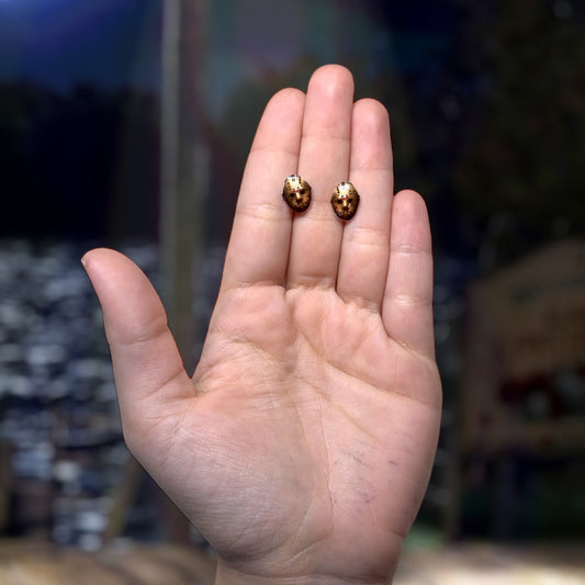 Friday the 13th-inspired Jason Voorhees hockey mask resin stud earrings being held