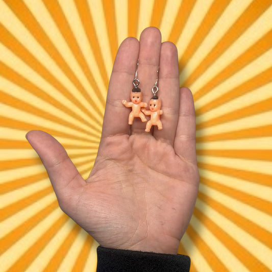 Little plastic babies statement dangle earrings being held