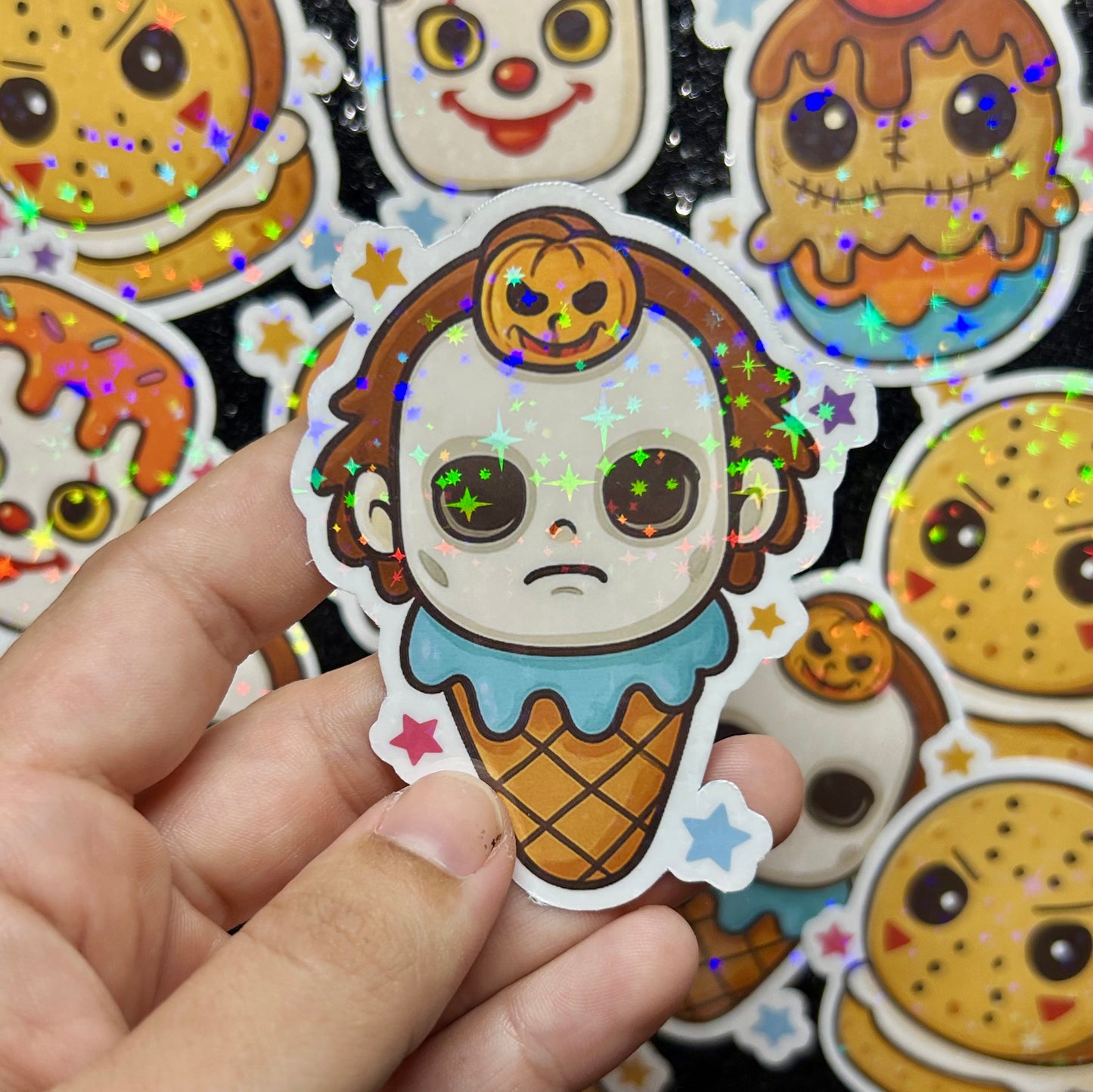Hand holding a Halloween Michael Myers ice cream cone with colorful stars against a background of similar stickers.