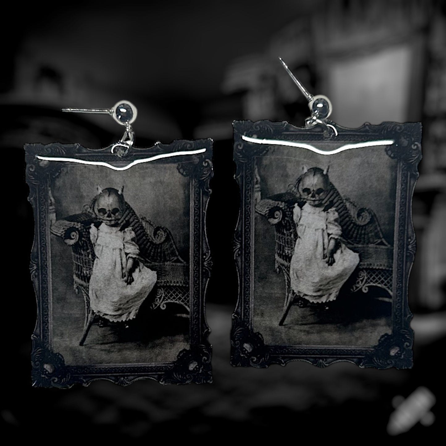 A pair of earrings featuring a vintage black and white framed art of a spooky pumpkin-headed baby.