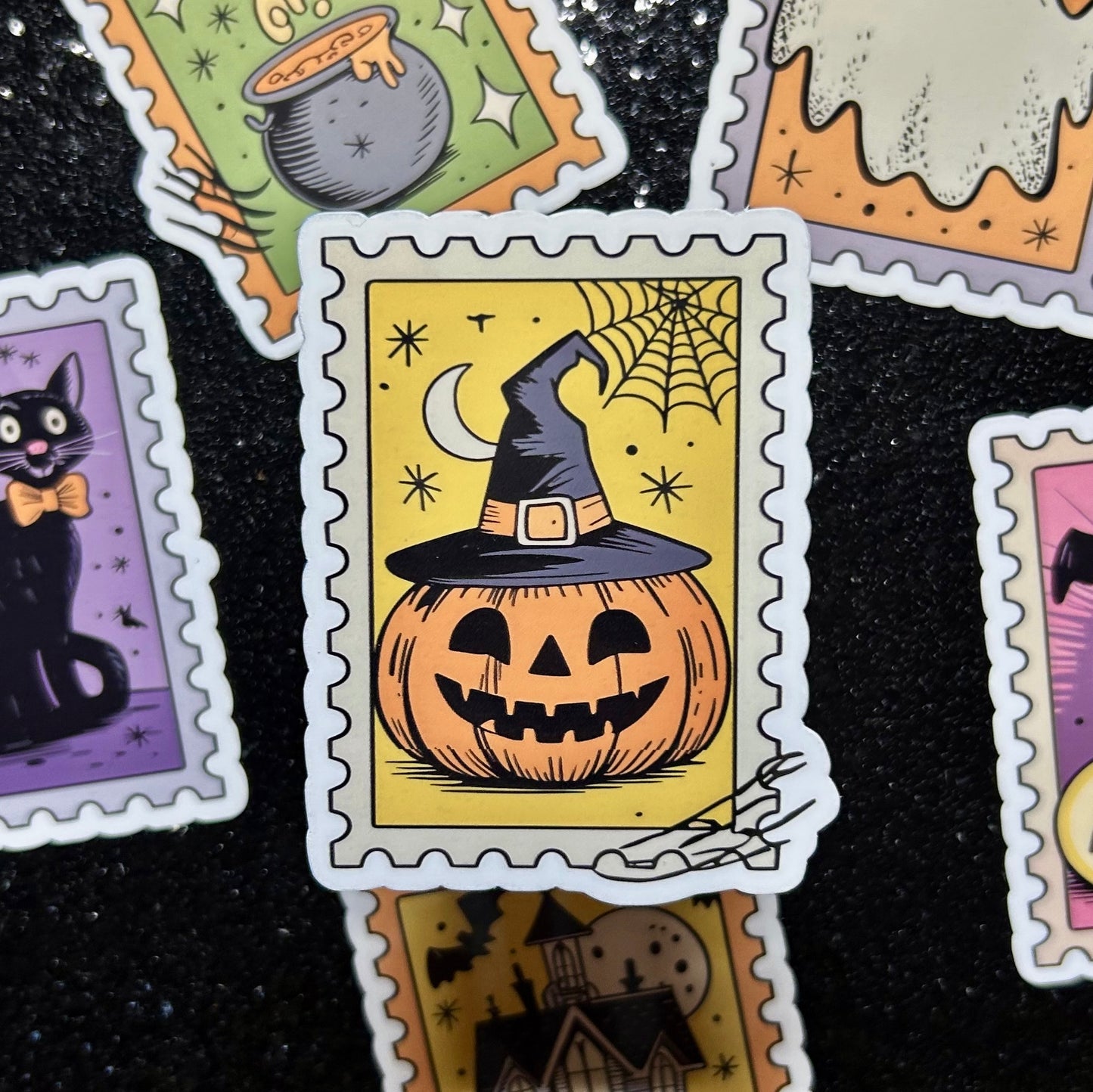 Sticker of a pumpkin wearing a black witch hat on a yellow background surrounded by similar Halloween-themed stamp stickers.