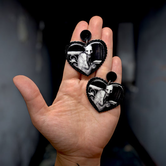 Russian Sleep Experiment Creepypasta heart-shaped resin statement earrings being held