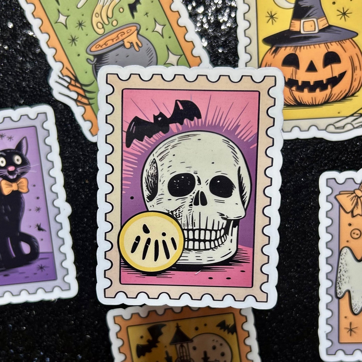 Sticker of a skull on a pink and purple background surrounded by similar Halloween-themed stamp stickers.