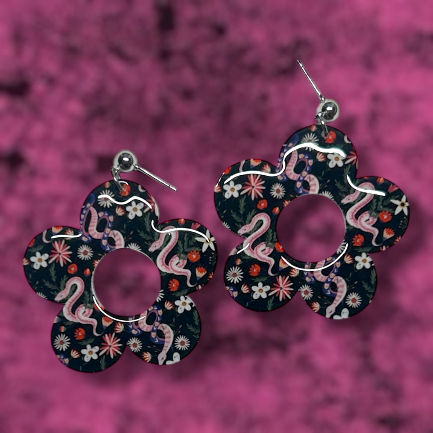 Floral and snake flower mod earrings on a pink background