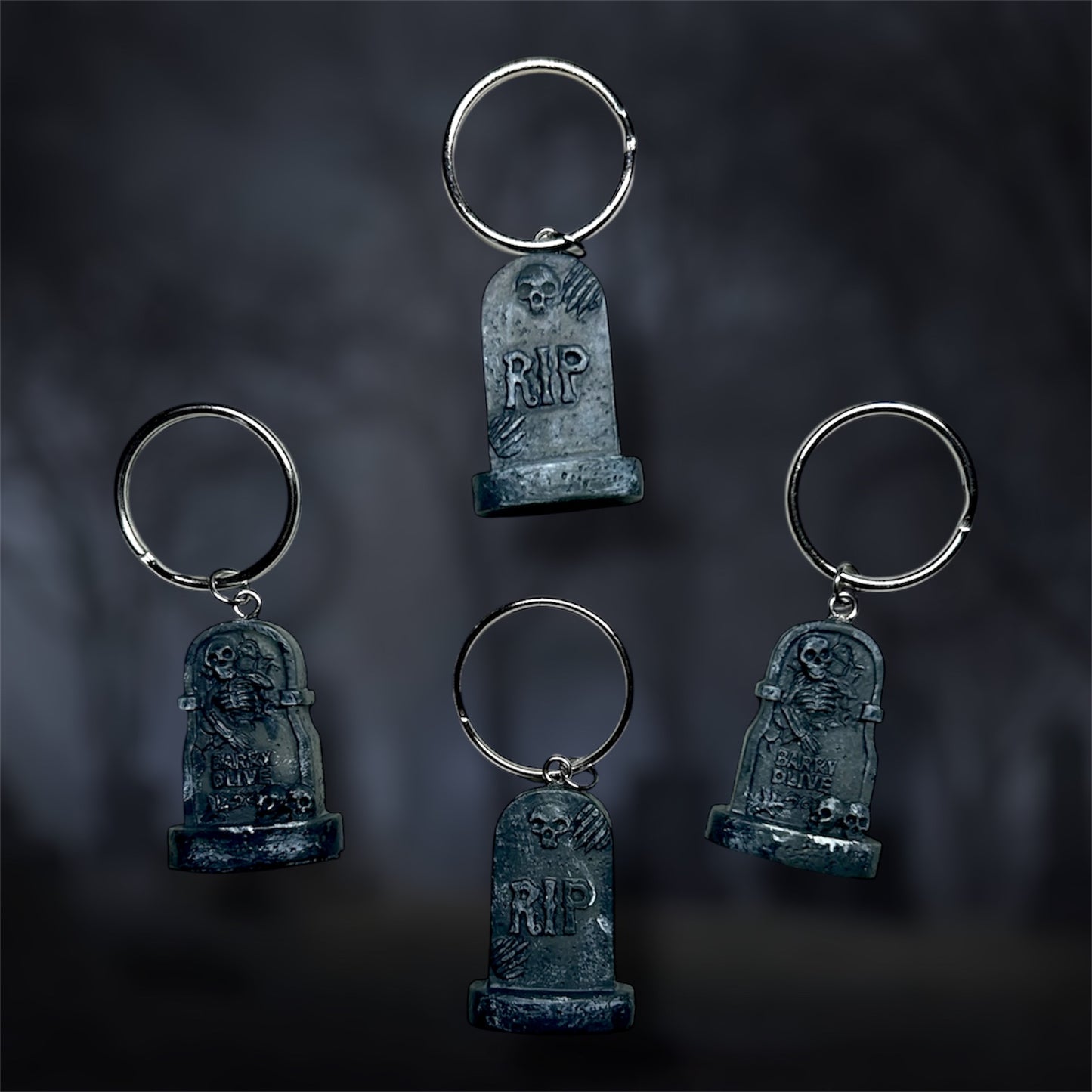 Four tombstone keychains with 'RIP' on a dark background