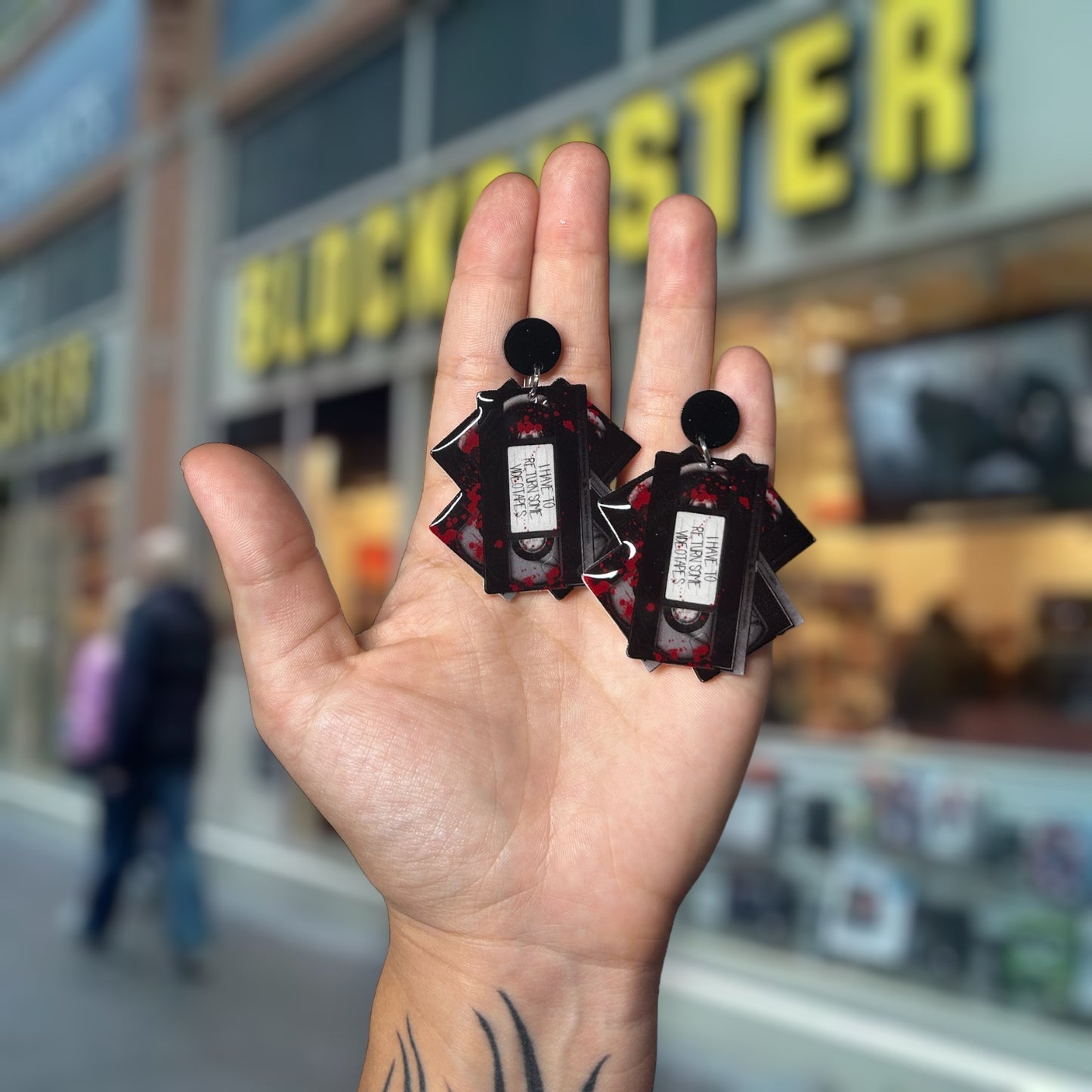 American Psycho-inspired I Have to Return Some Videotapes Patrick Bateman quote resin statement earrings being held