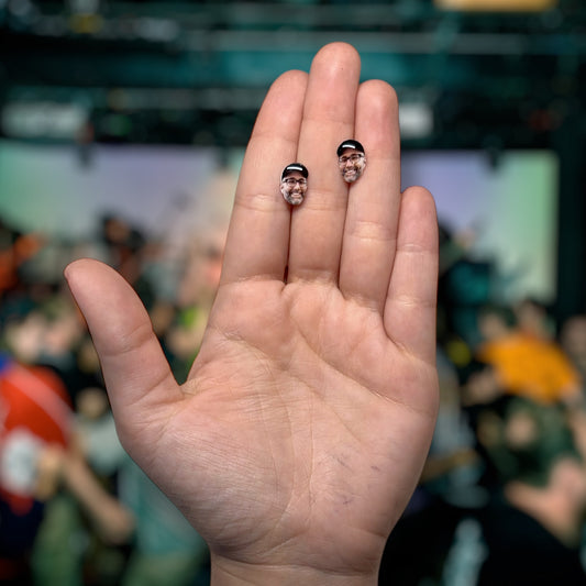 The Acacia Strain Vincent Bennett face resin stud earrings being held