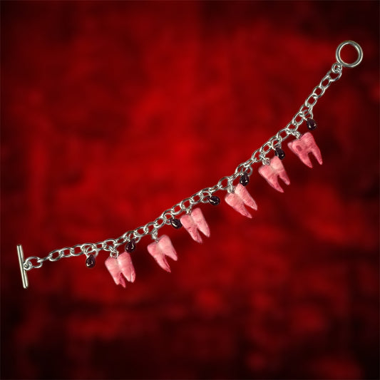 Unfastened bloody molars and blood drops charm bracelet on a blurred red background