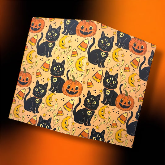 Open Halloween notebook with three-eyed black cats, pumpkins, ghosts, and candy corn on a black and orange background.