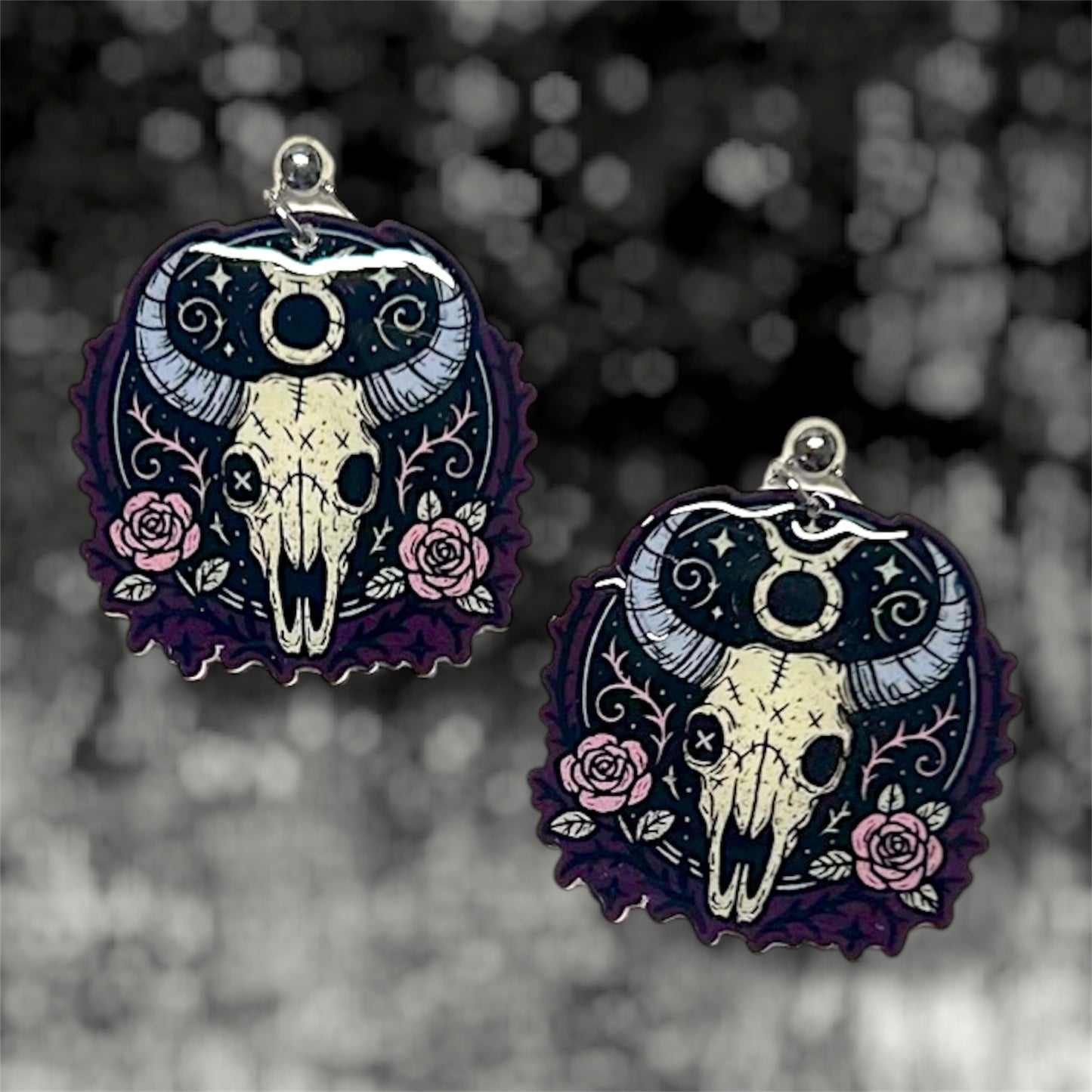 Taurus zodiac sign skeleton floral bull skull dangle earrings on a blurry black and white background