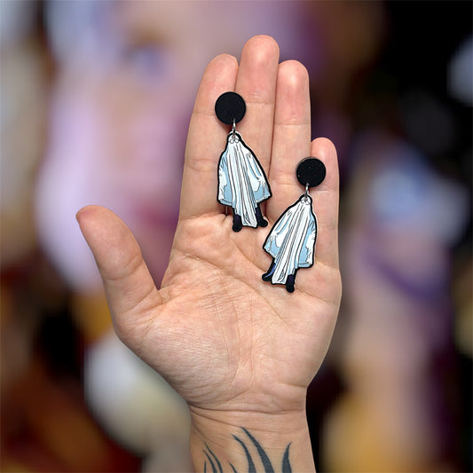 Hand holding a pair of Halloween Michael Myers sheet ghost resin dangle earrings on a blurry background
