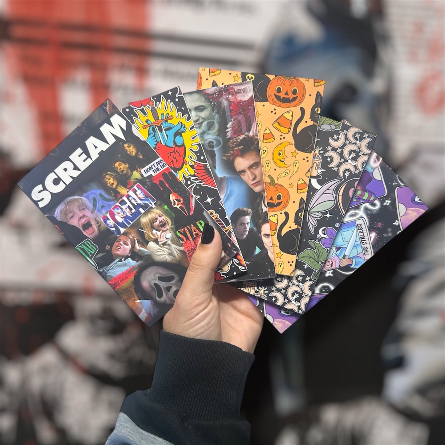 Hand holding colorful horror pocket notebooks on a blurry background