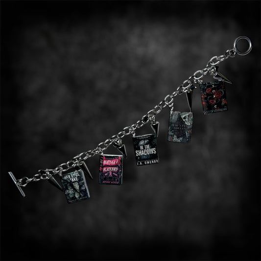 Unfastened smut book charm bracelet on a blurred black distressed background