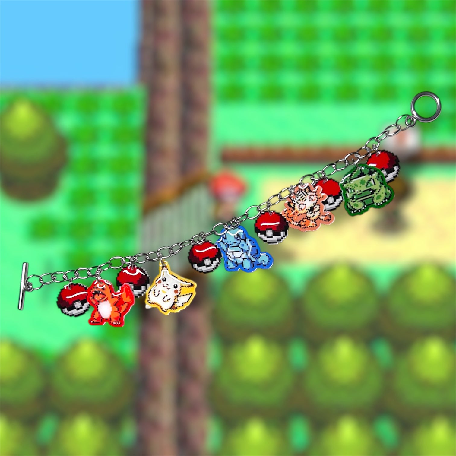 Unclasped 8-bit starter Pokemon art charm bracelet with Pokeballs on a blurred gameplay screencap background
