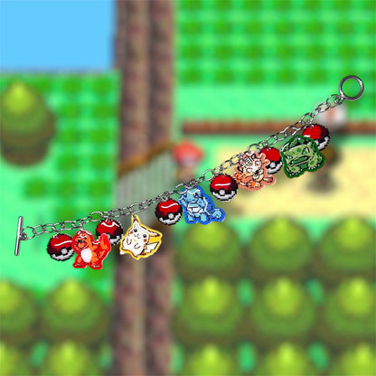 Unclasped 8-bit starter Pokemon art charm bracelet with Pokeballs on a blurred gameplay screencap background