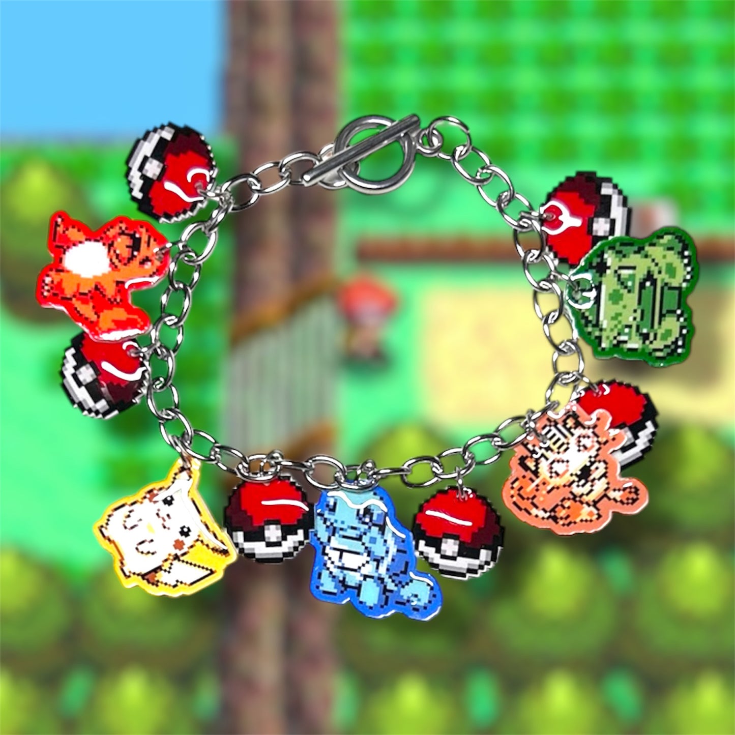 8-bit Pokemon art charm bracelet, including Charmander, Pikachu, Squirtle, Meowth, and Bulbasaur, with Pokeballs on a blurred gameplay screencap background