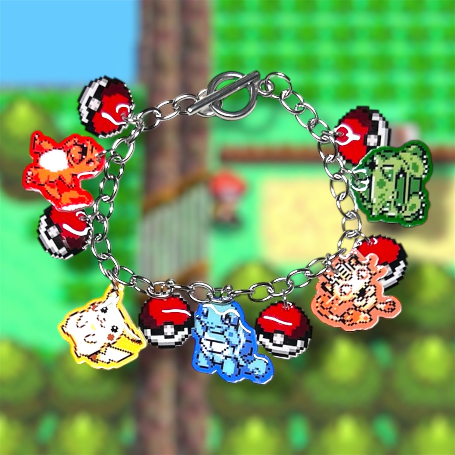 8-bit Pokemon art charm bracelet, including Charmander, Pikachu, Squirtle, Meowth, and Bulbasaur, with Pokeballs on a blurred gameplay screencap background