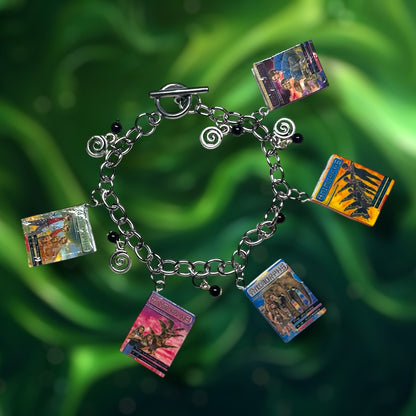Bracelet with Animorphs books, black glass beads, and swirl charms on a green background.