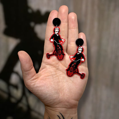 SAW Billy riding tricycle creepy puppet resin statement earrings being held
