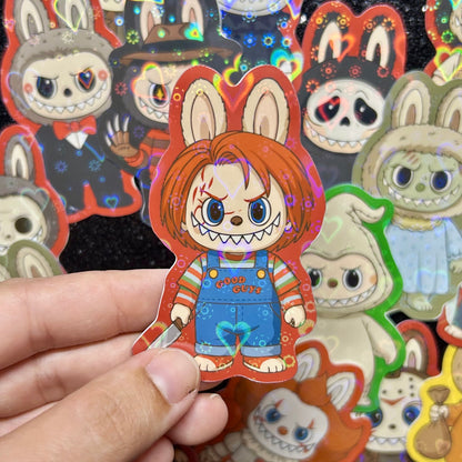 Hand holding a sticker of a Child's Play Chucky Labubu sticker, surrounded by other colorful stickers on a black background