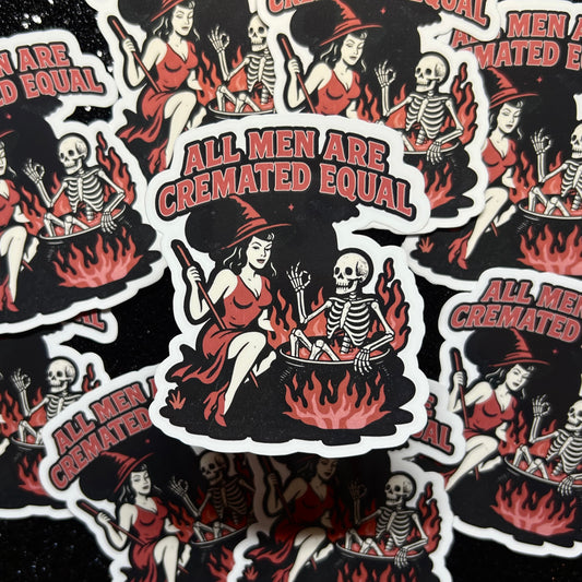 Sticker with skeleton in cauldron over fire and woman dressed like a witch and text 'All Men Are Cremated Equal' on a black background.