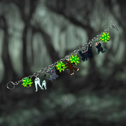 Bracelet with cryptids including the Fresno nightcrawler, Chupacabra, Bigfoot, Mothman, and the Jackalope and spiky green rubber beads on a dark background.