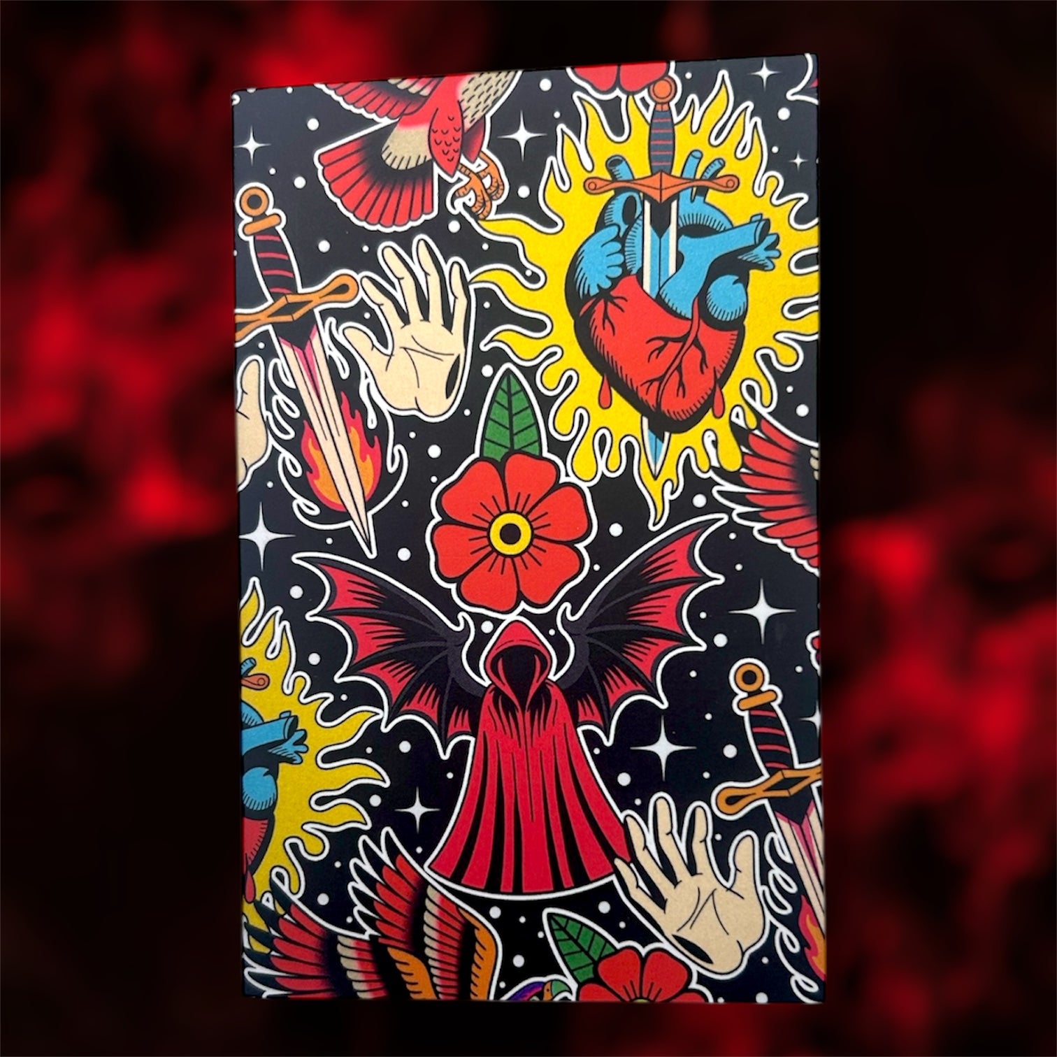 The front cover of a pocket notebook of a dark romance fantasy collage design on a blurred red and black background 