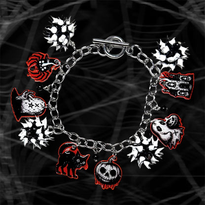 Black, white, and orange Halloween charm bracelet with black and white rubber spiky beads on a black and white blurry background