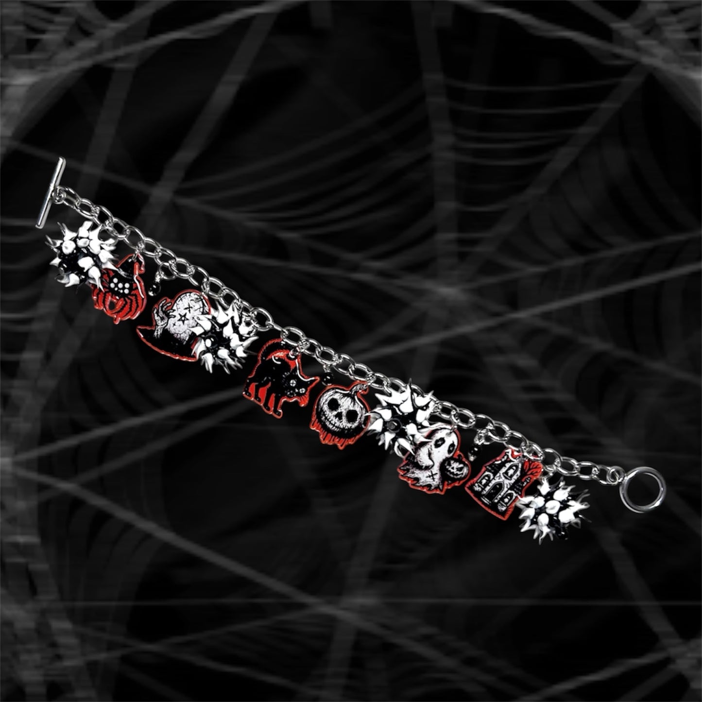 Black, white, and orange Halloween charm bracelet with black and white rubber spiky beads on a black and white blurry background