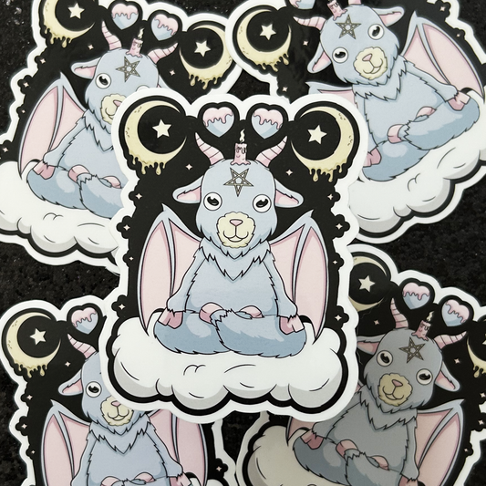 Stickers of a pastel-colored baphomet demon goat sitting on a cloud with celestial, witchy designs.