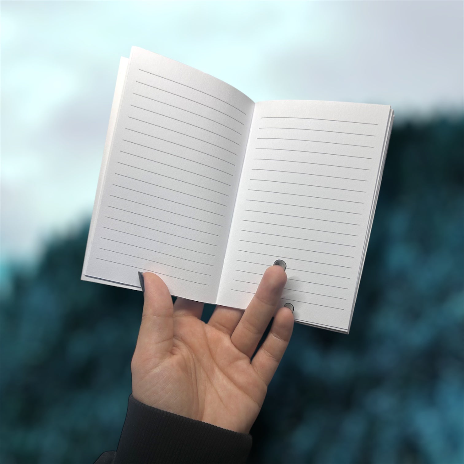 Hand holding an open pocket notebook with lined pages on a blurred blue background
