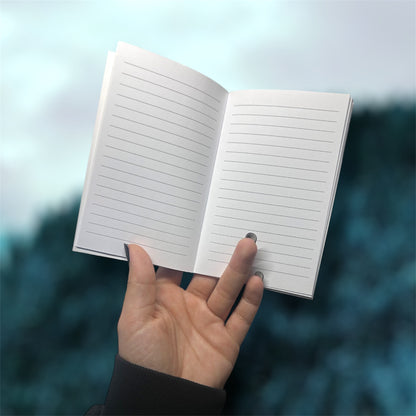 Hand holding an open pocket notebook with lined pages on a blurred blue background