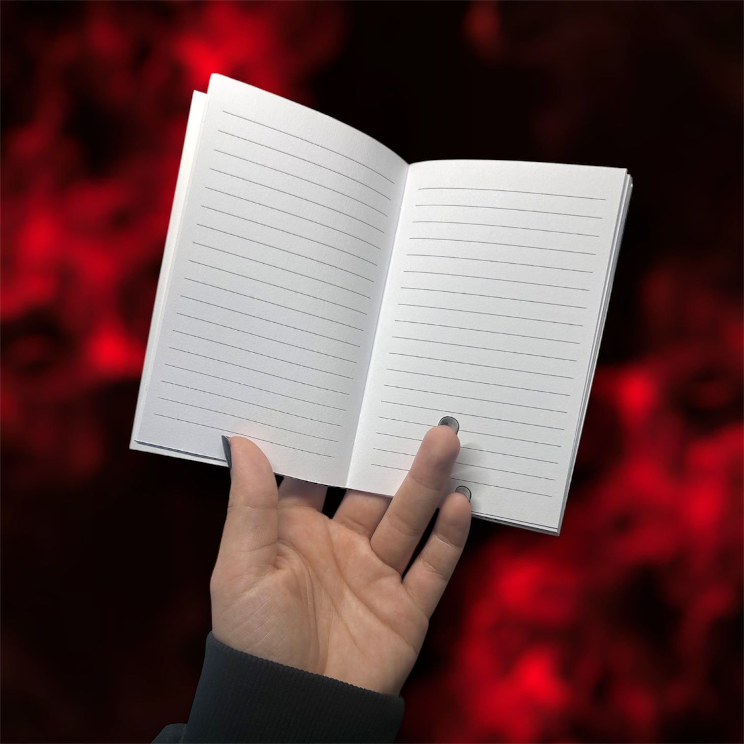 Hand holding an open pocket notebook with lined pages on a blurred red and black background