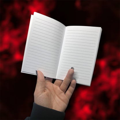 Hand holding an open pocket notebook with lined pages on a blurred red and black background