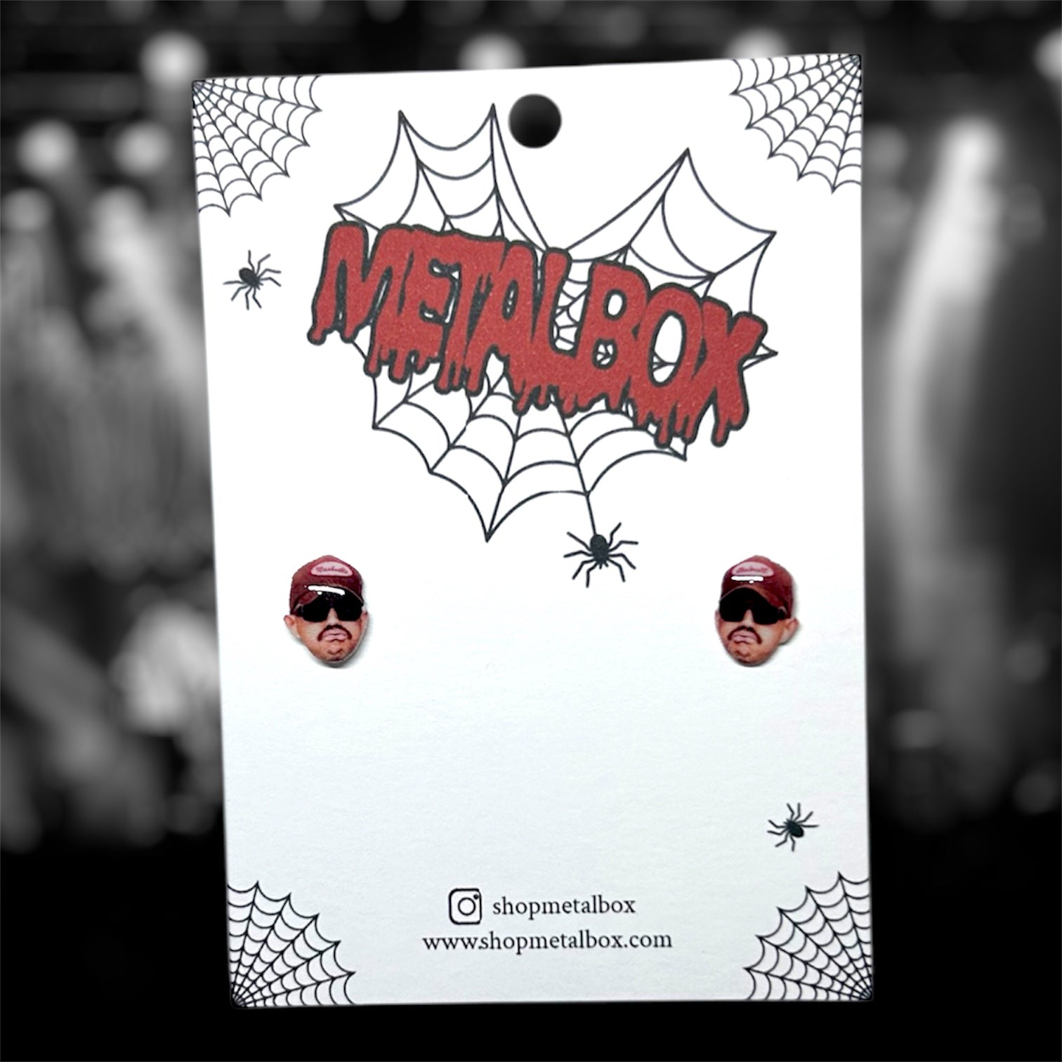 Kublai Khan Matt Honeycutt resin stud earrings on a blurry black and white background