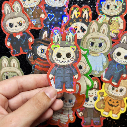 Hand holding a sticker of a Halloween Michael Myers Labubu sticker, surrounded by other colorful stickers on a black background