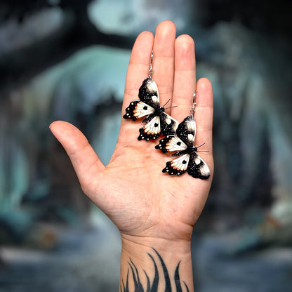 Moth resin statement earrings being held