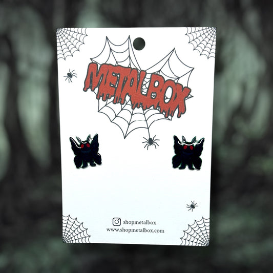 Mothman cryptid stud earrings on a blurred background.