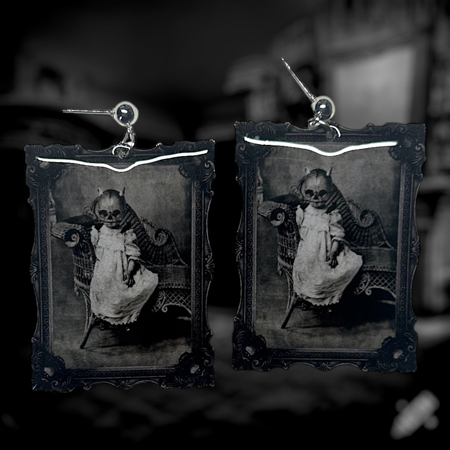 A pair of earrings featuring a vintage black and white framed art of a spooky pumpkin-headed baby. 