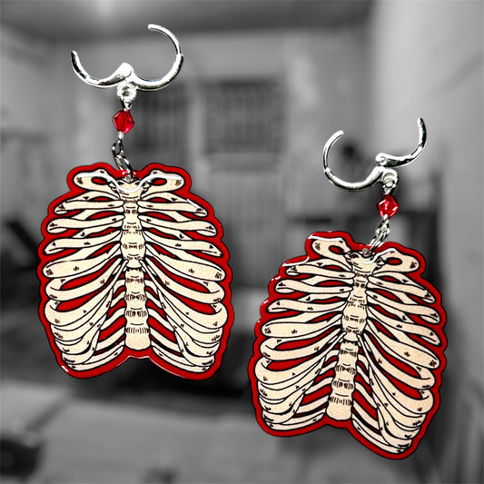 Glowing red ribcage beaded earrings on a blurred black and white background.