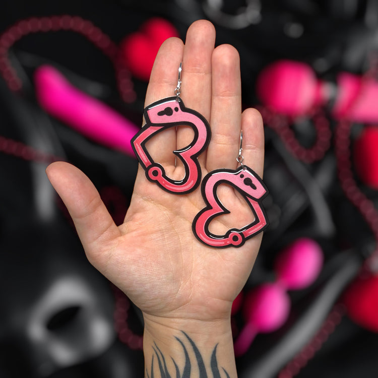 Single heart handcuffs BDSM kinky Valloween resin statement earrings being held